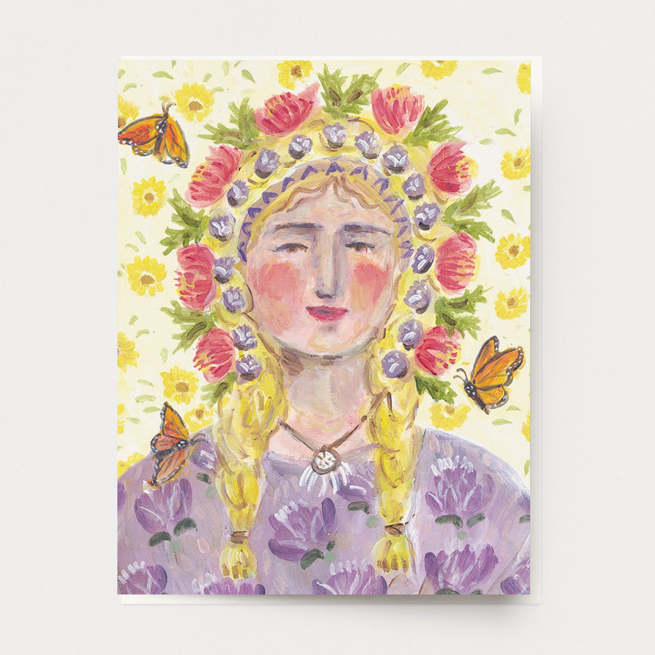 A greeting card of a peaceful blond woman with a colorful floral crown, a background of yellow flowers, a purple floral dress and monarch butterflies flying around. Hand illustrated and made by Ingrid Press card and gift company, ethically printed in the USA.