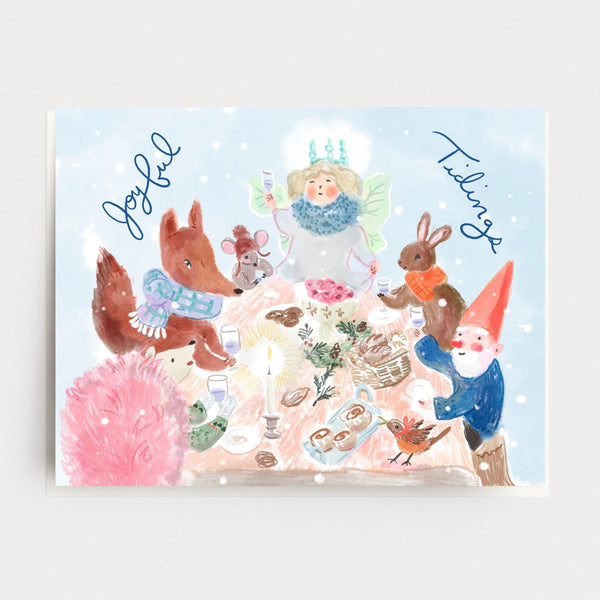 Illustrated holiday card with animals and a fairy around a table with food, on a light blue background.