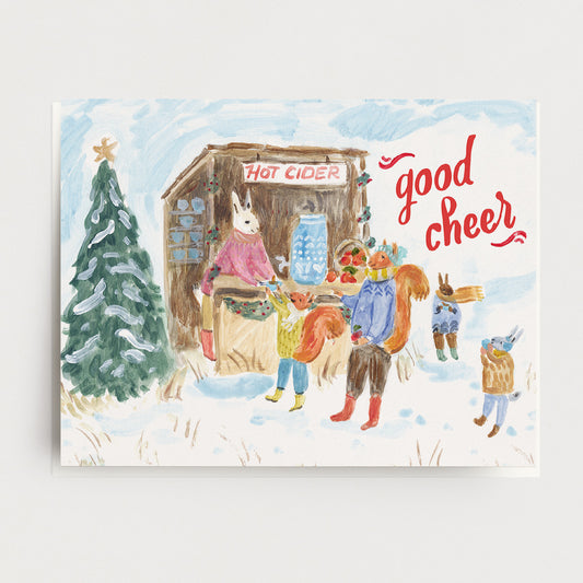 A holiday card with woodland animals getting hot cider from a festive stall and the words, Good Cheer. Ingrid Press, made in the USA